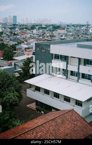 Jakarta, le 6 février 2025. Vue aérienne d'un bâtiment gouvernemental au milieu de maisons résidentielles et de gratte-ciel lointains. Banque D'Images