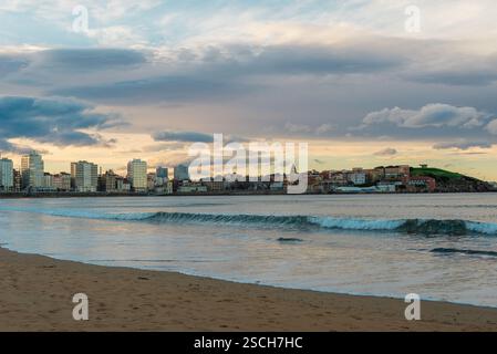 Vue sur la ville PRÈS DE LA MER PENDANT l'heure dorée et les vagues Banque D'Images