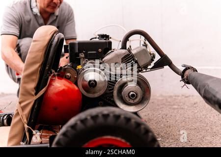 Cropped méconnaissable Man se concentre sur la réparation d'un moteur rouge, mettant en valeur les compétences mécaniques et la précision Banque D'Images