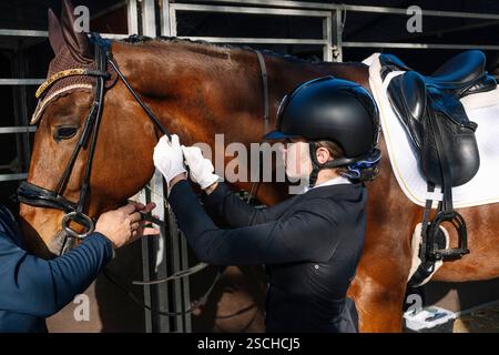 Un cavalier en tenue formelle et casque prépare un cheval pour un événement de dressage classique la scène capture la précision et l'élégance de ce d équestre Banque D'Images