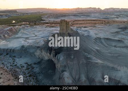 Une vue aérienne panoramique capture le vaste terrain érodé du désert de l'Utah au coucher du soleil, mettant en évidence les formations géologiques complexes et la décoloration douce Banque D'Images