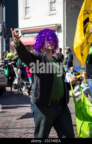 Homme en perruque violette distribuant des friandises à la parade. Banque D'Images