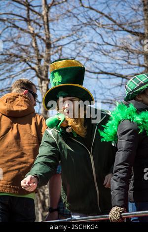 Défilé de la fête de Patrick. Homme en chapeau de leprechaun distribuant des friandises. Participant possible à la parade. Banque D'Images