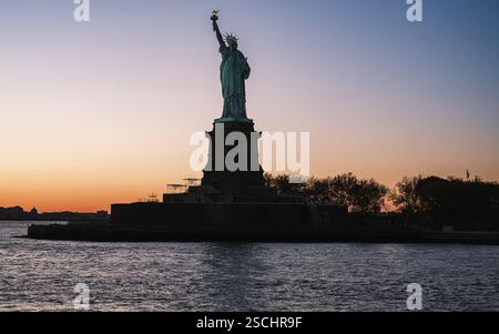 Au coucher du soleil, une silhouette époustouflante de la Statue de la liberté se dresse sur Liberty Island, New York. Le monument emblématique symbolise la liberté et l’espoir. Banque D'Images