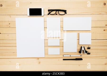 Espace de travail avec papeterie, smartphone et lunettes sur une table en bois Banque D'Images