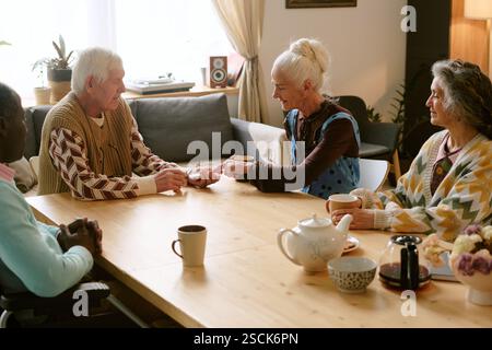 Plan à angle élevé d'un groupe biracial de retraités assis à une table en bois et aux cartes à jouer Banque D'Images
