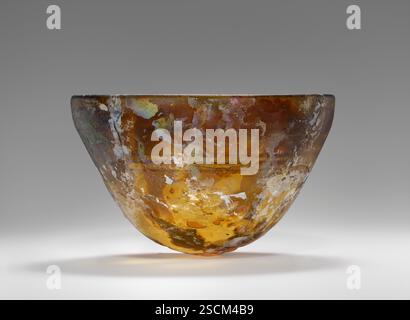 Bol, 2e-1er siècle av. J.-C. Informations supplémentaires : bol moulé de verre de couleur ambre. L'intérieur est incisé avec trois anneaux. Les intempéries importantes donnent au vaisseau une irisation, en particulier à l'intérieur. Il y a aussi une incrustation importante. Le bol a été reconstruit à partir de fragments. Banque D'Images