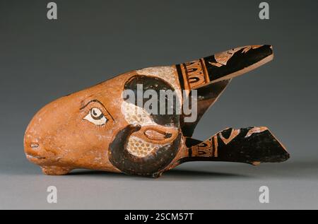 Attic Red-figure Dimidiated Rhyton, environ 450-425 av. J.-C. Informations complémentaires : la moitié de cette rhyton est moulée en forme de tête de bélier ; l'autre côté est celui d'un âne. Une bande de cymation sépare les têtes d'animaux de la décoration de la figure qui orne la bouche incomplètement préservée. Un Ménad court vers la gauche, poursuivi par un satyre, dont il ne reste qu'une jambe et la queue. Banque D'Images