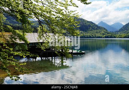 Une maison de bateau en bois sur le magnifique lac alpin vert émeraude Alpsee dans les Alpes allemandes à Hohenschwangau près des châteaux Hohenschwangau et Neuschwanstein Banque D'Images
