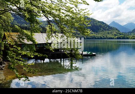 Une maison de bateau en bois sur le magnifique lac alpin vert émeraude Alpsee dans les Alpes allemandes à Hohenschwangau près des châteaux Hohenschwangau et Neuschwanstein Banque D'Images