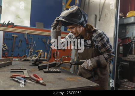 Femme soudeuse exécutant avec succès le processus de soudage MIG dans l'atelier de l'entreprise familiale. Artisans, inspiration et concepts de croissance personnelle. Banque D'Images