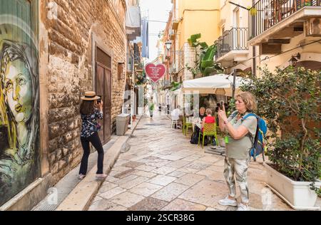 Bari, Pouilles, Italie - 10 octobre 2023 : une rue pavée étroite avec des bars et des restaurants en plein air dans le centre historique de Bari. Banque D'Images