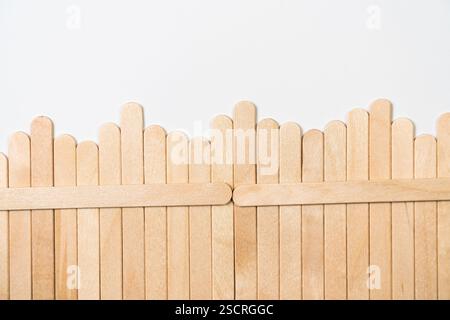 Clôture en bois faite de bâtons Popsicle sur fond blanc Banque D'Images