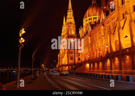 Budapest, Hongrie - 24 novembre 2024 : le bâtiment illuminé du Parlement hongrois se dresse majestueusement à côté de la rivière la nuit, mettant en valeur son étourdissement Banque D'Images