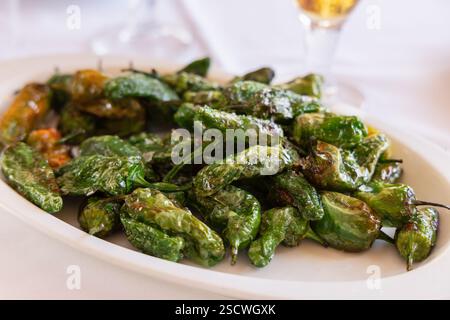Apéritif espagnol traditionnel avec des piments de Padron frits 9Pimiento de Padron) garni de gros sel, placé sur une assiette blanche dans un repos rustique Banque D'Images