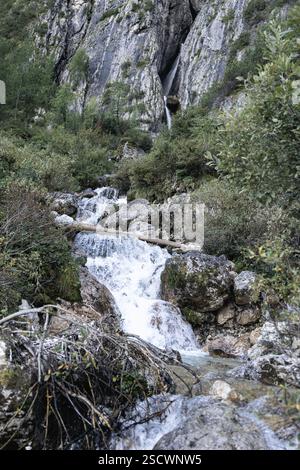 Une vue verticale des cascades de Pisciadu dans les Dolomites avec de l'eau précipitée, des falaises rocheuses, une végétation alpine et la beauté naturelle des montagnes Banque D'Images