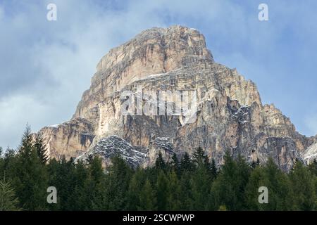 La montagne Sassongher est haute avec sa façade rocheuse touchée par les chutes de neige précoces, encadrée par des arbres verts vibrants et un ciel serein dans les Dolomites Banque D'Images