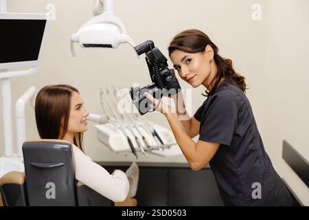 Femme dentiste photographiant avec un appareil photo professionnel le résultat de son travail en clinique. Banque D'Images