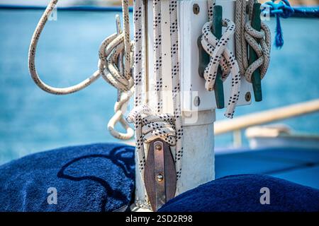 Vue rapprochée de cordes résistantes et endommagées solidement fixées autour du mât d'un navire, mettant en évidence le savoir-faire artisanal et le gréement essentiel de la voile maritime Banque D'Images