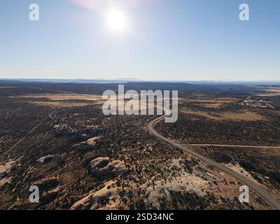 Vue aérienne à angle élevé d'une route asphaltée sinueuse traversant le vaste paysage désertique en direction du parc national de Canyonlands dans l'Utah Banque D'Images