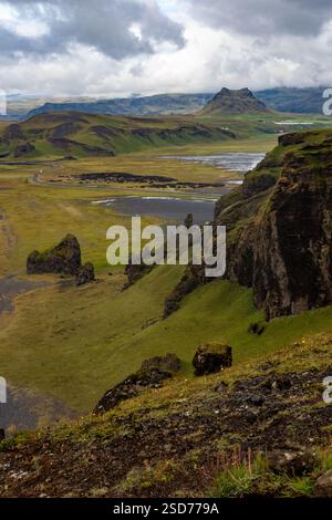 Vue côtière à couper le souffle près de la plage noire de reynisfjara et des montagnes à distance VIK d'un sommet une falaise, entouré de paysages spectaculaires et le Banque D'Images