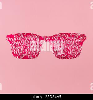 Disposition de luxe à la mode faite avec des diamants visibles à travers des lunettes en forme de découpe sur fond rose. Concept esthétique de mode beauté minimale. Pose à plat, Banque D'Images