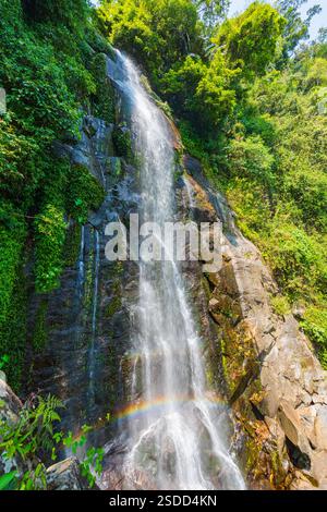 Cascade descendant une falaise rocheuse avec un arc-en-ciel Banque D'Images