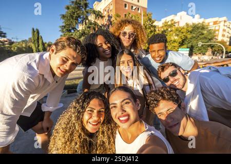 Vue frontale d'un groupe de jeunes gens divers prenant selfie dans la rue souriant à la caméra Banque D'Images