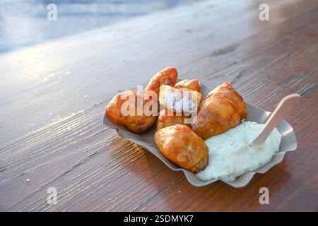Pâte à bière frite frite morceaux de morue avec sauce remoulade sur un carton sur une table en bois, emporter plat de poisson à un grill de fruits de mer côtier sur le port, Banque D'Images