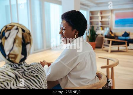 Dans un environnement de bureau moderne, deux collègues sont vus rire et profiter de la compagnie de l'autre. Leur interaction amicale met en évidence un travail e positif Banque D'Images