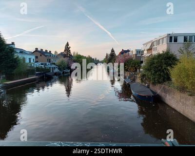 Vue sur une voie navigable avec des arbres en fleurs et des bateaux des deux côtés, près d'Amstedam au printemps 2022 Banque D'Images