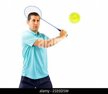 portrait d'un jeune joueur masculin de badminton debout et frappant la balle isolé sur fond blanc Banque D'Images