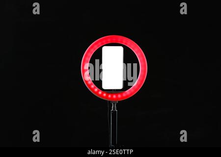 Lampe annulaire avec smartphone sur fond noir Banque D'Images