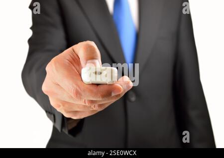 Homme d'affaires avec une télécommande dans sa main et isolé avec fond blanc Banque D'Images
