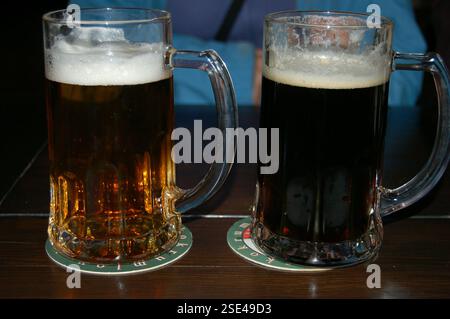 Deux grandes tasses de bière tchèque brune et bière ALE avec une tête mousseuse sur une table en bois rustique, mettant en valeur la riche couleur et la texture de la bière traditionnelle Banque D'Images