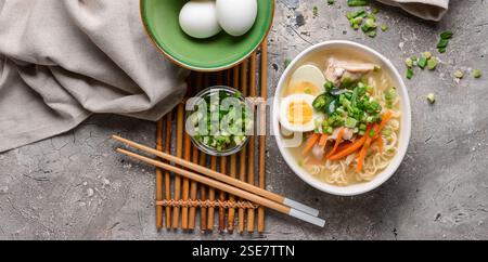 Composition avec soupe savoureuse de nouilles ramen sur fond gris, vue de dessus Banque D'Images