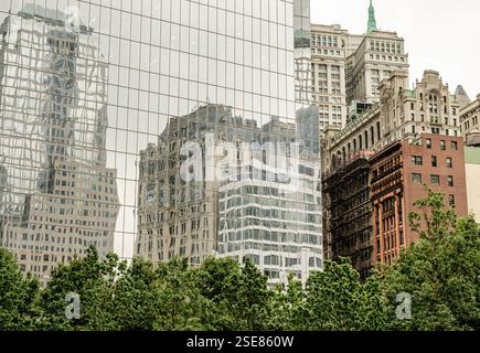 Dans un paysage urbain, les grands bâtiments se reflètent sur une façade en verre épurée. Le mélange d'architecture ancienne et nouvelle met en valeur le développement de la ville contre A. Banque D'Images