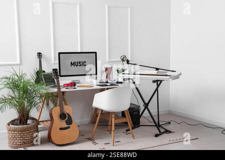 Lieu de travail avec ordinateur et instruments de musique près du mur de lumière dans le studio Banque D'Images