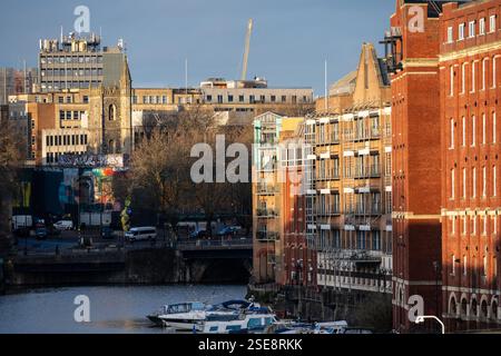 Le soleil brille sur la tour de l'église St Mary le Quay et les immeubles d'appartements le long de Redcliffe Quay sur le port flottant de Bristol. Banque D'Images