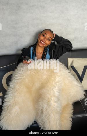 Soirée cosy avec services de streaming : une jeune femme profite de ses spectacles préférés, détendue sur un canapé confortable Banque D'Images
