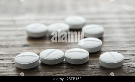 Les comprimés blancs sont soigneusement alignés sur une surface en bois texturée, mettant en valeur leur uniformité et leur simplicité. Banque D'Images