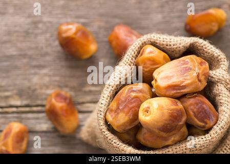 Dattes, savoureux fruits secs dans sac de toile ou bol sur fond rustique en bois, nourriture kareem ramadan, point sélectif de l'espace de copie (Phoenix dactylifera ) Banque D'Images
