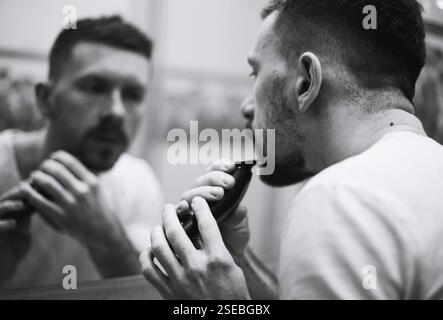 un gars se rase devant un miroir Banque D'Images