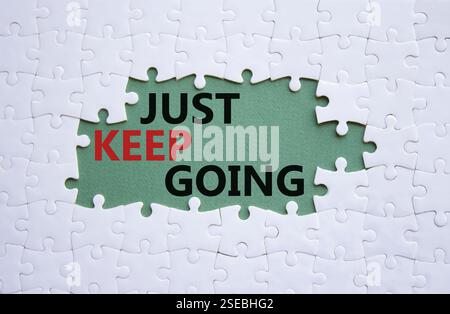 Symbole « continuez à aller ». Puzzle blanc avec des mots juste continuer. Beau fond vert gris. Business and Just Keep Go concept. Copier l'espace. Banque D'Images