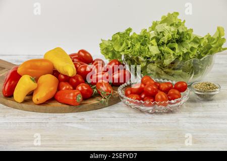 Tomates fraîches, poivrons colorés et laitue sur une table de cuisine dans un cadre lumineux Banque D'Images