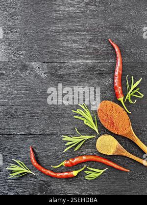 Image de branches de romarin frais, gousses de piment rouge et deux cuillères avec le poivre noir sur fond de bois d'en haut Banque D'Images