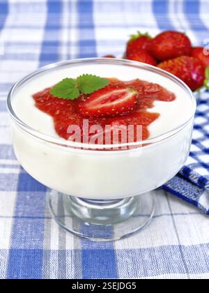 Dessert aux fraises lait et le yogourt dans un bol en verre sur un fond de lin bleu Banque D'Images