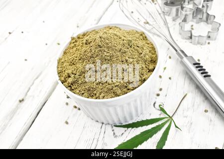 Farine dans un bol, mixer et d'un emporte-pièce, feuilles de cannabis sur l'arrière-plan des panneaux en bois Banque D'Images