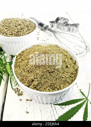 Et la farine de chanvre industriel dans des bols blanc, mixer et d'un emporte-pièce, feuilles de cannabis sur l'arrière-plan de planches en bois Banque D'Images