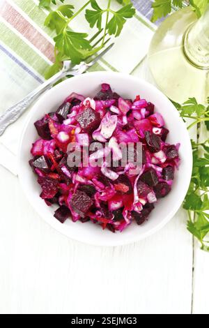 Salade Vinaigrette au vinaigre ou avec de la choucroute, pommes de terre, betterave et l'oignon, assaisonnés avec de l'huile végétale dans un bol, serviette, le persil sur l'arrière-plan o Banque D'Images